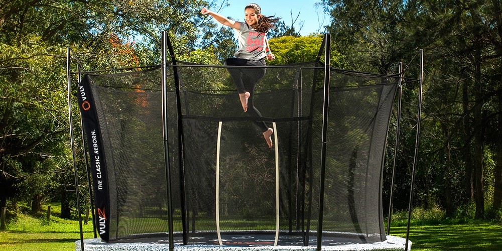 Girl bouncing on trampoline with safety netting