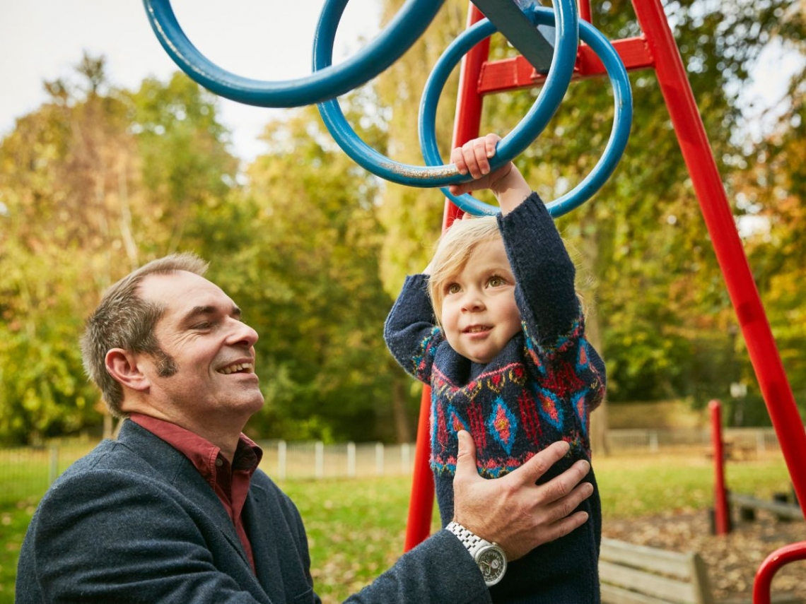 a father helping his young son on monkey bars.jpg