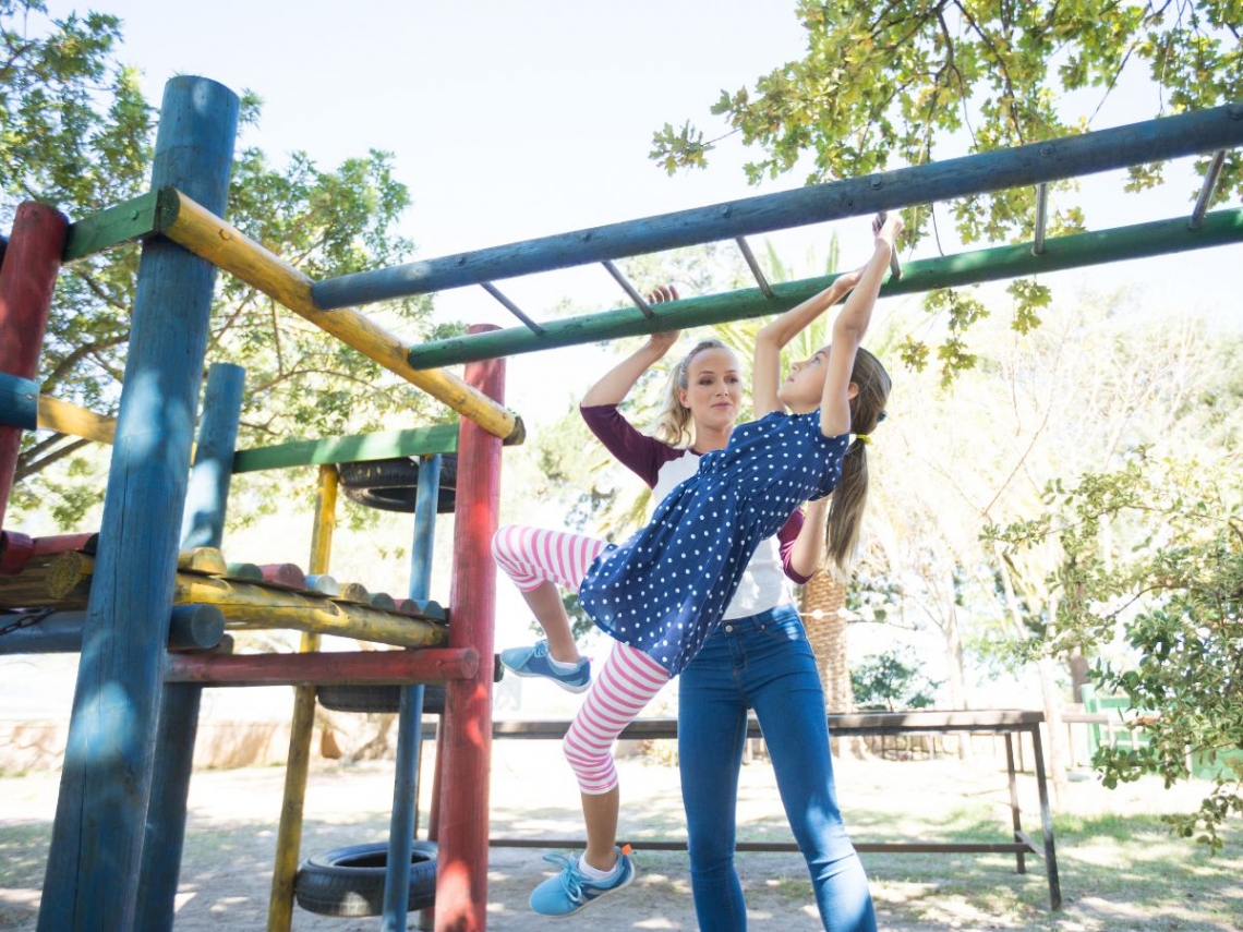 a mother helping her daughter on monkey bars.jpg
