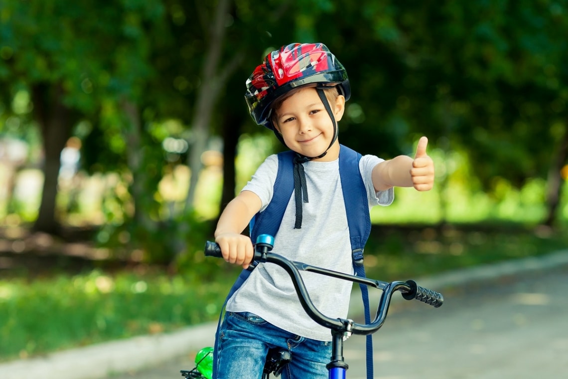 Kid on bike giving the thumbs up