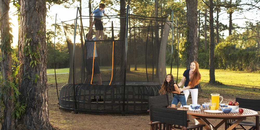 Kids bouncing on a Vuly trampoline while parents watch sitting down