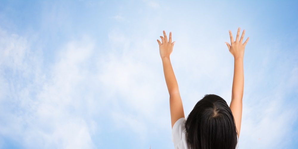 Girl putting both arms up into the sky