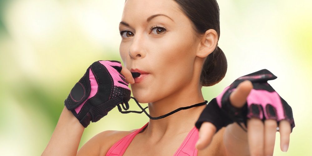 Woman in pink attire blowing a whistle and ready for exercise
