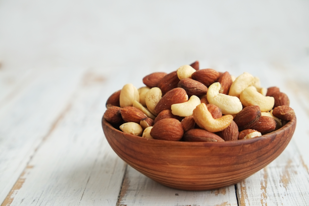 Various nuts in a wooden bowl sitting on a table