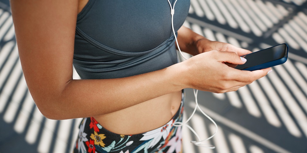 Woman selecting music on her phone with headphones