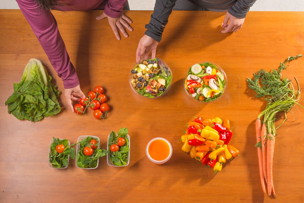 People conducting meal prepping with vegetables and containers 