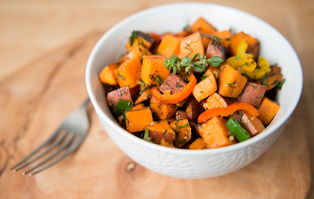 Sweet potato in white bowl with a fork placed on a table