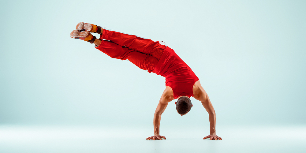 Guy handstanding while flexing to the side