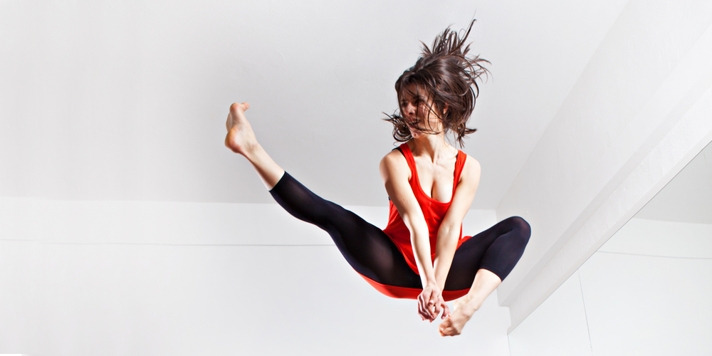 Girl jumping up and kicking on a trampoline.