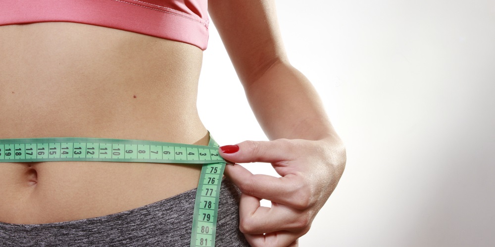 Woman measuring her waist with tape