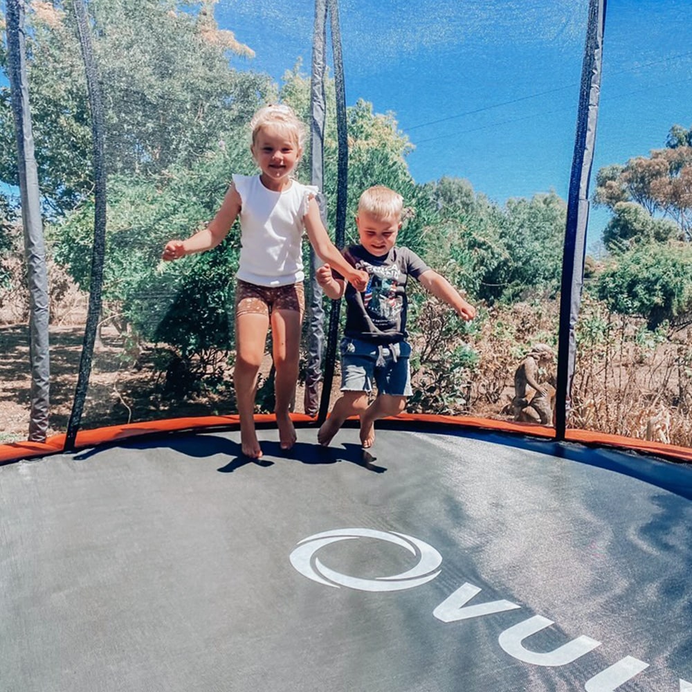 Sibling playing on their trampoline. 