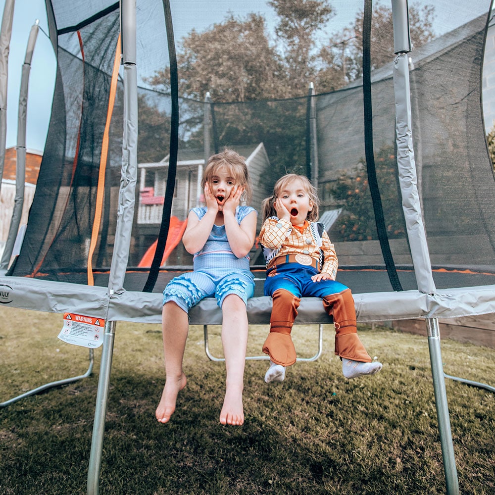 Young sisters playing on trampoline.